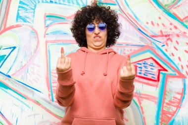 Genç, güzel afro kadın kışkırtıcı, agresif ve müstehcen hissediyor, orta parmağını şaklatıyor, duvarlara karşı isyankar bir tavırla