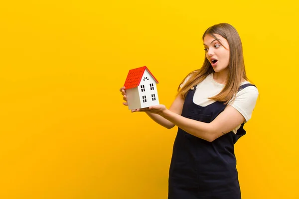 Jong Mooi Vrouw Met Een Huis Model Tegen Oranje Achtergrond — Stockfoto