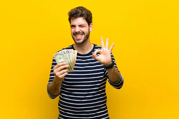 Fiatal jóképű férfi dollár bankjegyek ellen narancs backgrou — Stock Fotó