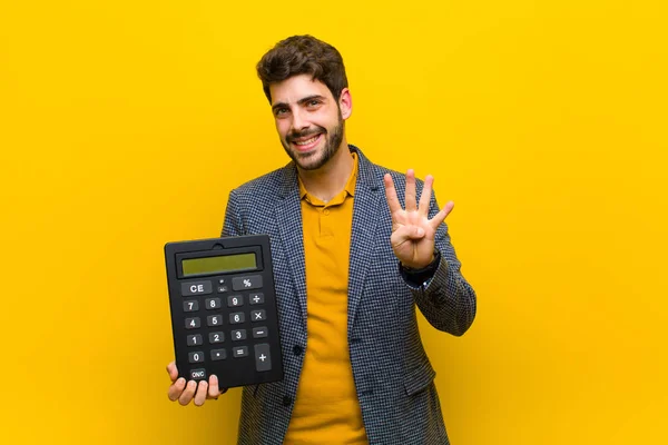 Jovem homem bonito com uma calculadora contra fundo laranja — Fotografia de Stock