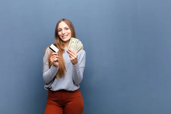 コピースペースのある青い壁にドル紙幣の若い女性が — ストック写真