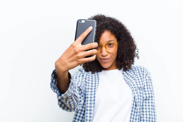 年轻漂亮的黑人女人 拿着智能手机靠着白墙 — 图库照片