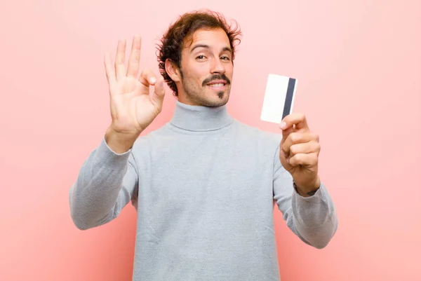 年轻英俊的男人 拿着信用卡靠着粉红的平板墙 — 图库照片