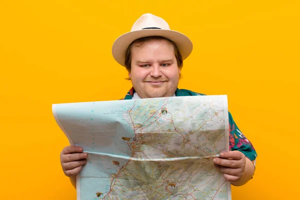 young big size man with a map against flat wall