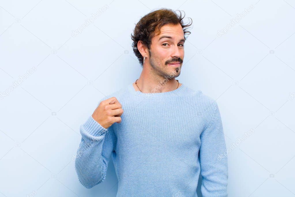 young handsome man looking arrogant, successful, positive and proud, pointing to self isolated against flat wall