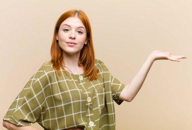 Genç kızıl saçlı güzel kadın gülümsüyor, kendinden emin, başarılı ve mutlu hissediyor, fotokopi alanında fikir veya konsept gösteriyor.