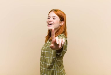 Genç kızıl saçlı güzel kadın gururla gülümsüyor ve bir numaralı pozunu başarıyla veriyor, kendini lider gibi hissediyor.