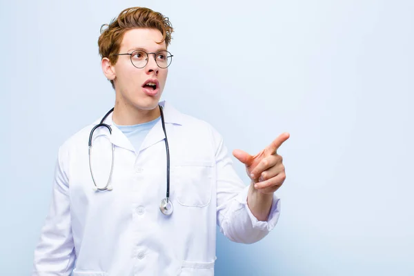 Young Red Head Doctor Feeling Shocked Surprised Pointing Looking Upwards — Stock Photo, Image