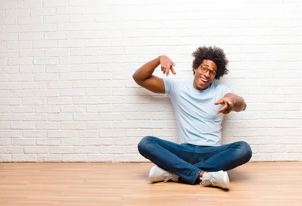 年轻的黑人男子兴高采烈 自信满满满的 双手对着相机笑着 选择你坐在家里的地板上 — 图库照片