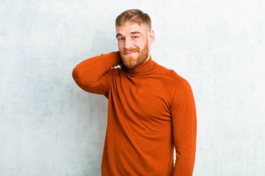 Kaplumbağa boynu takan genç, kızıl saçlı adam güler yüzlü, güler yüzlü, güler yüzlü çimento duvarına karşı güler yüzlü, güler yüzlü.