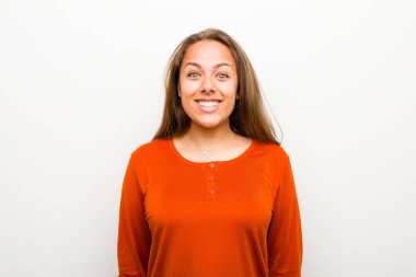 Genç bir kadın mutlu ve şapşal görünüyor. Geniş, eğlenceli, kaçık bir gülüşü ve beyaz arka planda gözleri açık.