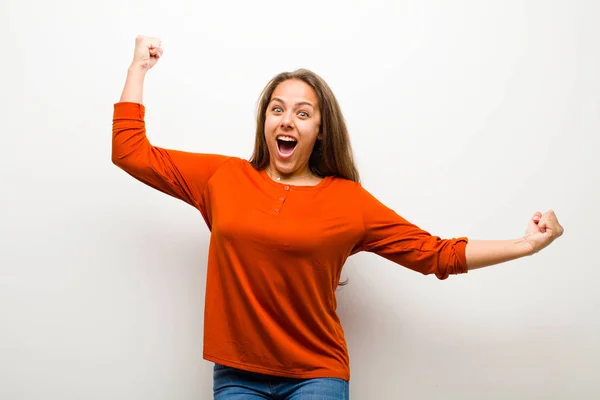 young woman shouting triumphantly, looking like excited, happy and surprised winner, celebrating against white background