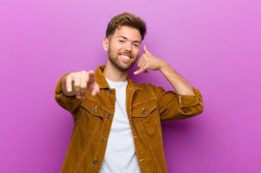 Genç adam neşeyle gülümsüyor ve kamerayı işaret ediyor. Daha sonra seni arıyor. Telefonda mor arka planda konuşuyor.