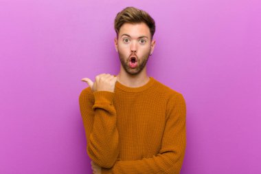 İnançsızlıktan şaşkın bakan genç adam, yan taraftaki objeyi işaret ederek ve 