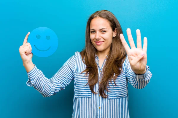 Jonge vrouw met een smiley gezicht tegen blauwe achtergrond — Stockfoto