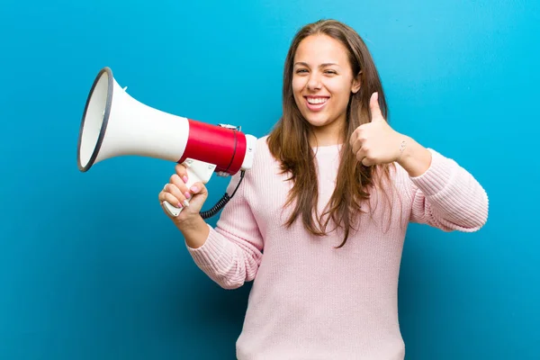 Jonge vrouw met een megafoon tegen blauwe achtergrond — Stockfoto