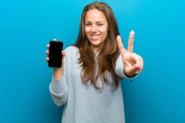 Giovane donna con un telefono cellulare sullo sfondo blu — Foto Stock