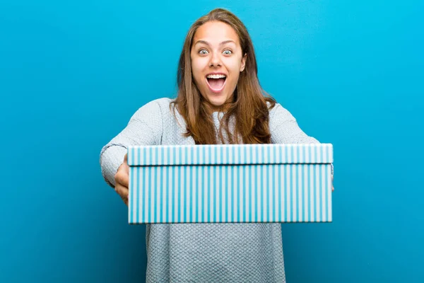 Mujer joven con una caja sobre fondo azul — Foto de Stock