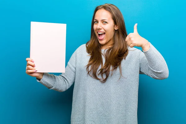 Jovem com um caderno contra fundo azul — Fotografia de Stock