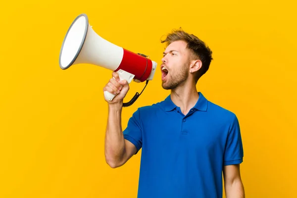 Joven con un megáfono sobre fondo amarillo —  Fotos de Stock