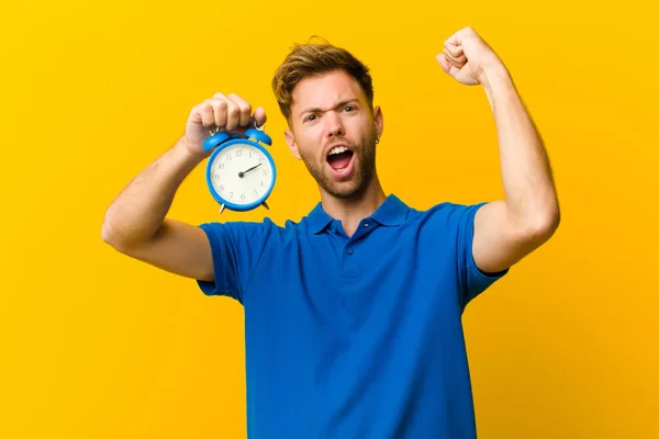 Jongeman Met Een Wekker Tegen Oranje Achtergrond — Stockfoto