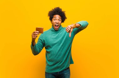 Cüzdanı turuncu arka Grou 'ya karşı olan Afrikalı Amerikalı genç bir adam.