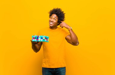 Turuncu sırt çantasına karşı hediye kutusu olan Afrikalı genç bir Amerikalı.