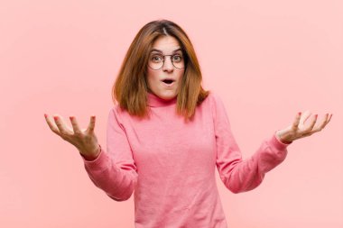 Genç ve güzel bir kadın açık sözlü ve şaşkın, şaşkın ve şaşkın pembe arka plana karşı inanılmaz bir sürpriz ile