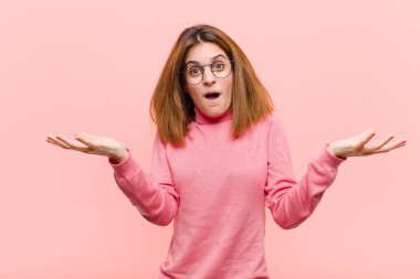 Genç ve güzel bir kadın son derece şaşkın, şaşırmış, endişeli ve paniklemiş hissediyor. Pembe arka planda stresli ve dehşete düşmüş bir bakışla.