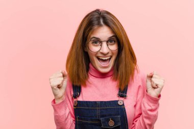 Genç, güzel bir kadın şok olmuş, heyecanlı ve mutlu, gülüyor ve başarıyı kutluyor, vay canına! Pembe arkaplan