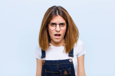 Şok olmuş, kızgın, hayal kırıklığına uğramış, ağzı açık ve öfkeli görünen genç bir kadın.