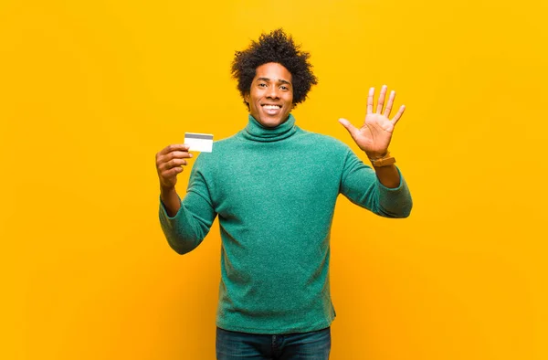 Mladý africký Američan s kreditní kartou proti oranžové bac — Stock fotografie