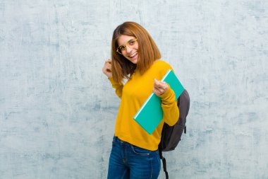 Genç bayan gülümsüyor, kaygısız, rahat ve mutlu hissediyor, dans ediyor ve müzik dinliyor, grunge Wall arka planındaki bir partide eğleniyor.