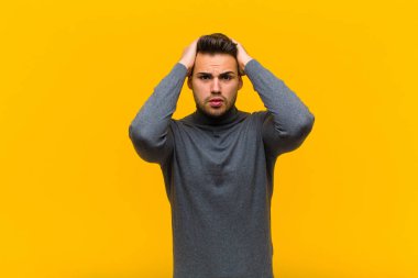 Genç İspanyol adam dehşete kapılmış ve şok olmuş hissediyor. Turuncu duvara karşı ellerini kaldırıyor ve panikliyor.