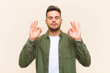 Genç İspanyol adam konsantre olmuş ve meditasyon yapıyor, kendini tatmin olmuş ve rahat hissediyor, düşünüyor ya da izole edilmiş arka plana karşı bir seçim yapıyor.