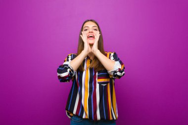 genç güzel kadın mutlu, heyecanlı ve olumlu duygu, ağız yanında elleri ile büyük bir çığlık veren, mor arka plan karşı seslenerek