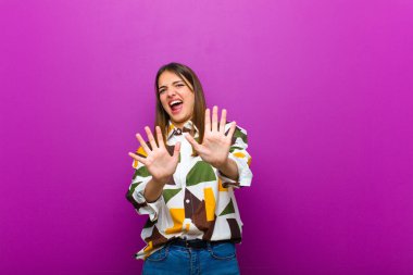 Genç ve güzel bir kadın korku ve panik içinde geri çekilip çığlık atıyor. Mor arka plana karşı bir kabusa tepki veriyor.