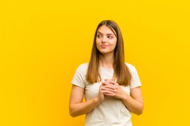 Genç, güzel bir kadın kötü bir plan yaparken gururlu, yaramaz ve kibirli hissediyor ya da turuncu arka plana karşı bir numara düşünüyor.