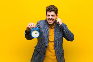 Çalar saati turuncu arka planda genç yakışıklı bir adam.