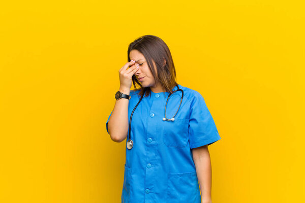 feeling stressed, unhappy and frustrated, touching forehead and suffering migraine of severe headache isolated against yellow wall