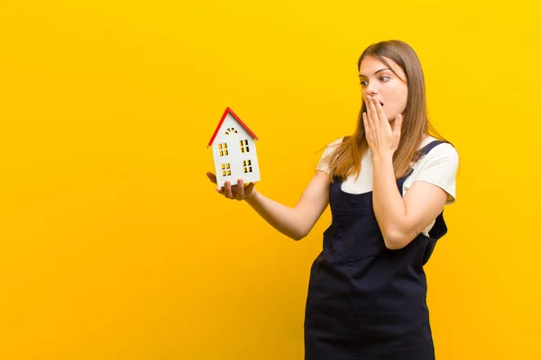 Jong Mooi Vrouw Met Een Huis Model Tegen Oranje Achtergrond — Stockfoto