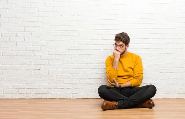 Joven Hombre Guapo Sentado Suelo Casa Contra Textura Pared Ladrillo —  Fotos de Stock