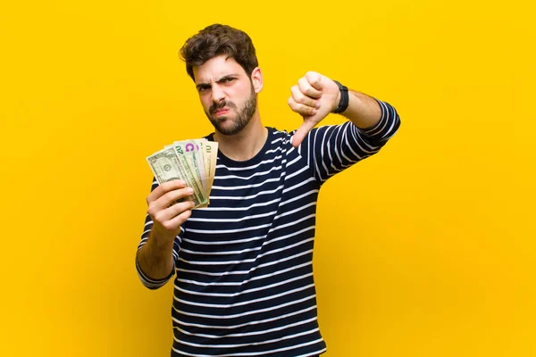Jonge knappe man met dollarbiljetten tegen oranje backgrou — Stockfoto