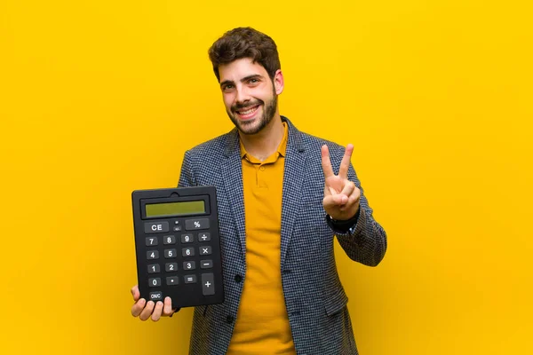 Fiatal jóképű férfi egy számológép narancssárga háttér — Stock Fotó