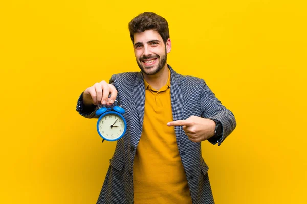 Jovem bonito homem com um despertador contra fundo laranja — Fotografia de Stock