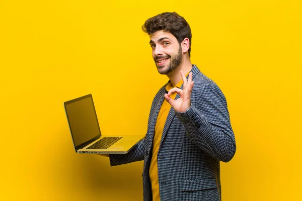 Junger schöner Mann mit Laptop vor orangefarbenem Hintergrund — Stockfoto