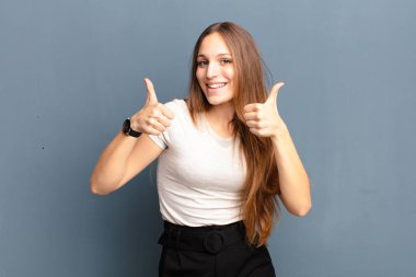 Genç ve güzel bir kadın mutlu, pozitif, kendine güvenen ve başarılı bir şekilde gülümsüyor.