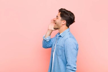 Genç yakışıklı profil görüntüsü, mutlu ve heyecanlı görünüyor, bağırıyor ve pembe arka planda yer almak için çağırıyor.