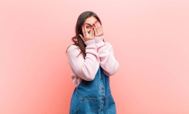 Genç, güzel bir kadın korkmuş ya da utanmış hissediyor. Gözleri yarı kapalı pembe arka planda dikizliyor ya da dikizliyor..