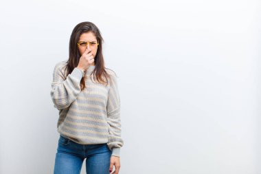 Genç ve güzel bir kadın iğreniyor, pis ve tatsız bir kokunun kokusunu almaktan kaçınmak için burnunu tutuyor.